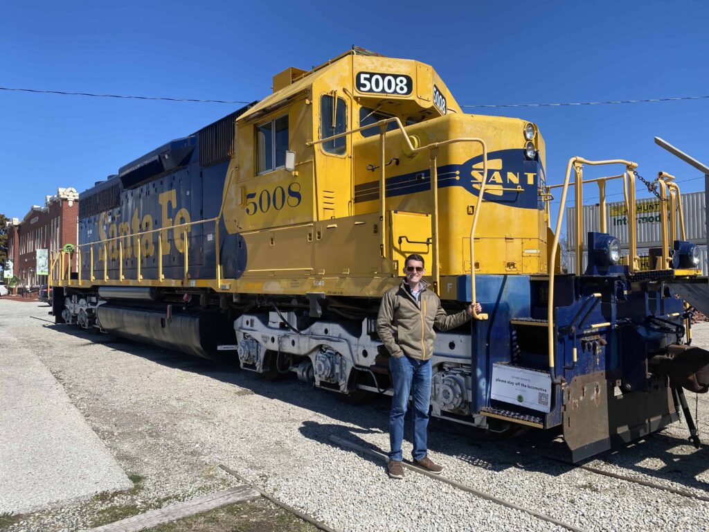 Josh standing in front of a yellow train